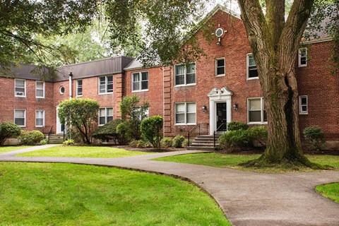 A red brick building with a tree in front.