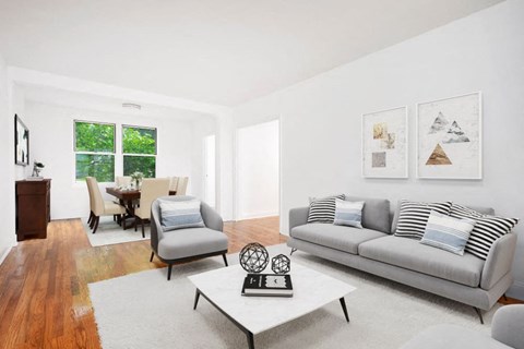A living room with a grey couch, a white coffee table, and a wooden floor.