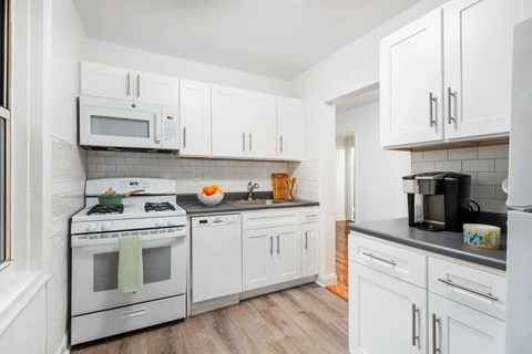 A kitchen with white cabinets and appliances.