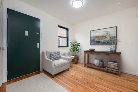 A room with a black door, a grey couch, a wooden shelf, and a potted plant.