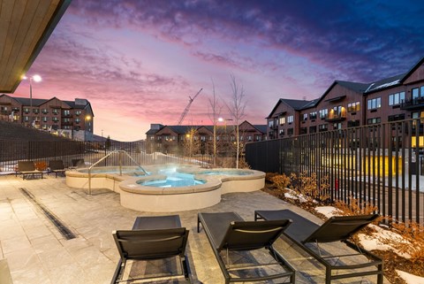 A hot tub sits in the middle of a patio with chairs around it.