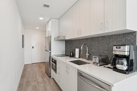 A modern kitchen with white cabinets and stainless steel appliances.
