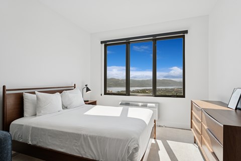 A bedroom with a large bed and a view of the mountains outside the window.