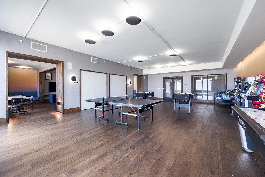 a large room with a ping pong table and a dining room with chairs and
