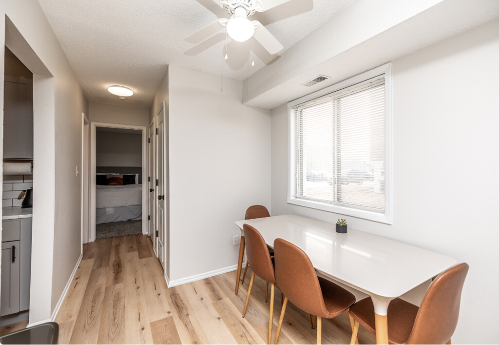 a dining room with a white table and chairs and a large window