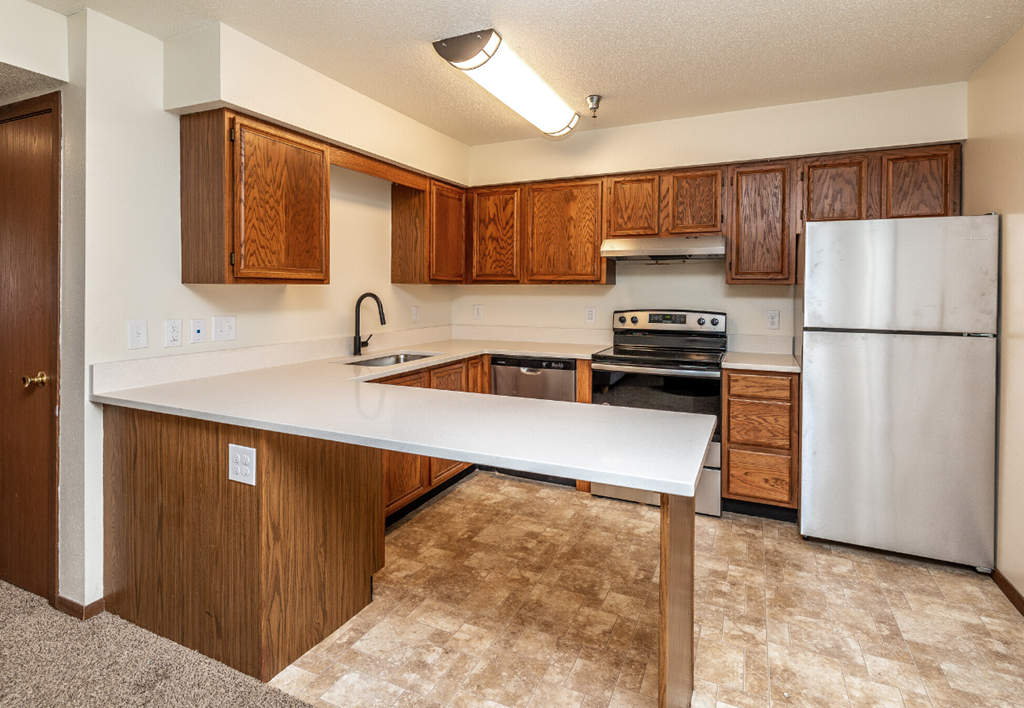 an empty kitchen with wood cabinets and stainless steel appliances