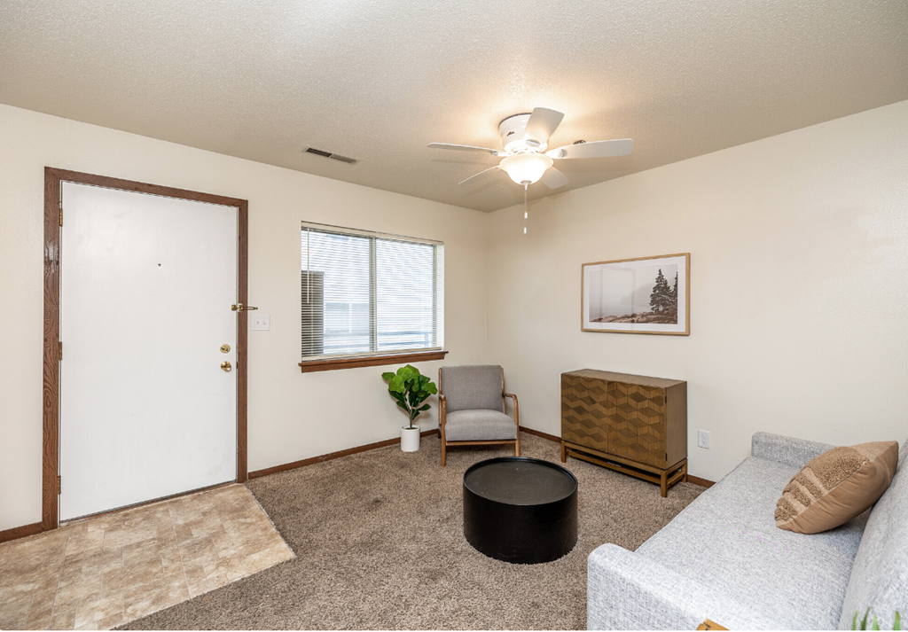 a living room with a couch and a chair and a ceiling fan