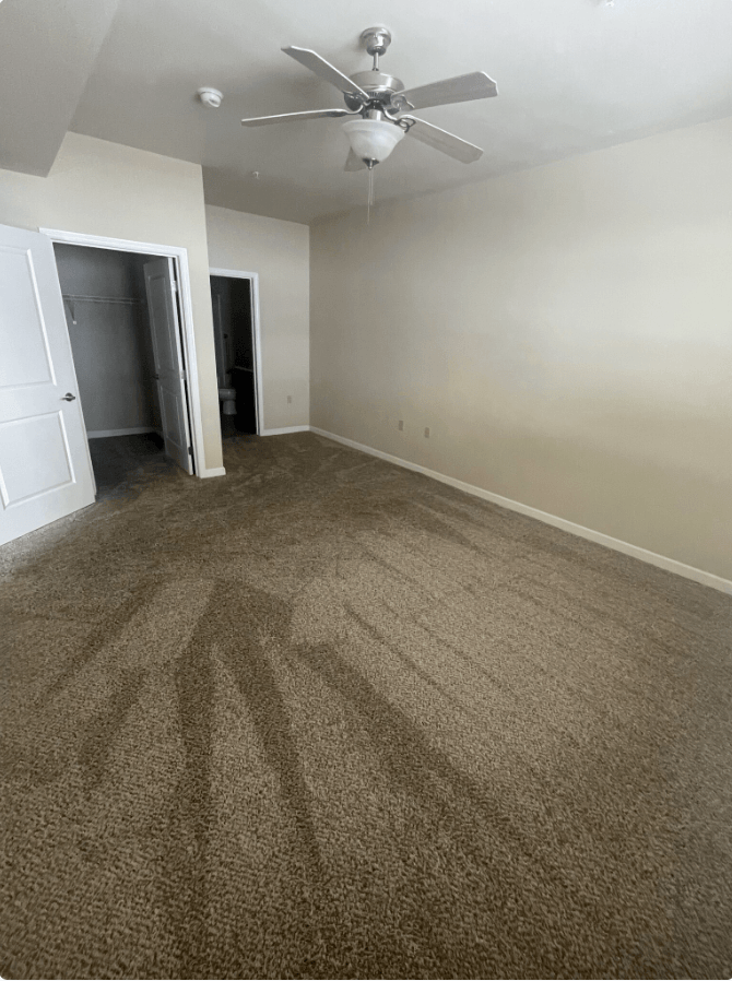 an empty living room with carpet and a ceiling fan