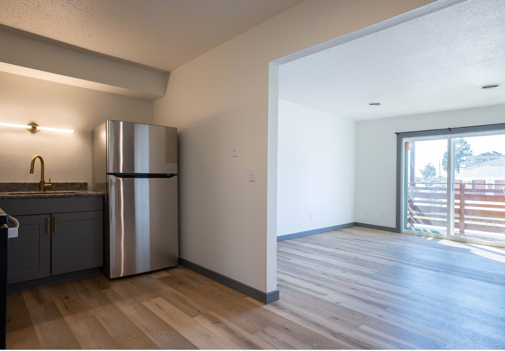 an empty kitchen with a stainless steel refrigerator and a sliding glass door