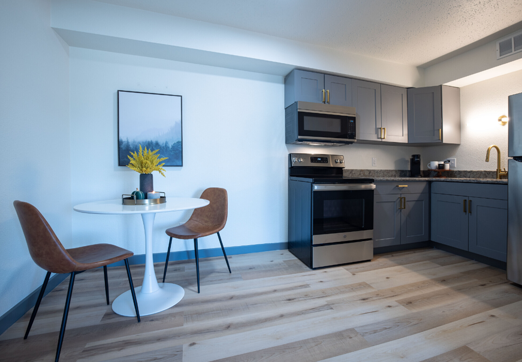 a kitchen and dining area with a table and chairs and a refrigerator and microwave