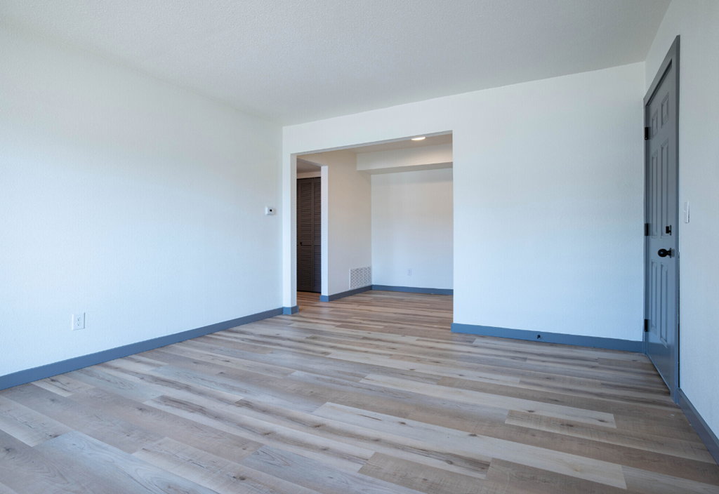 an empty living room with white walls and wood floors