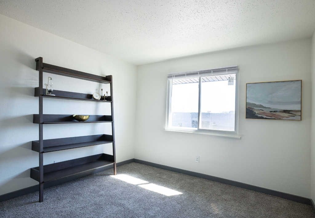 an empty room with a window and a shelf