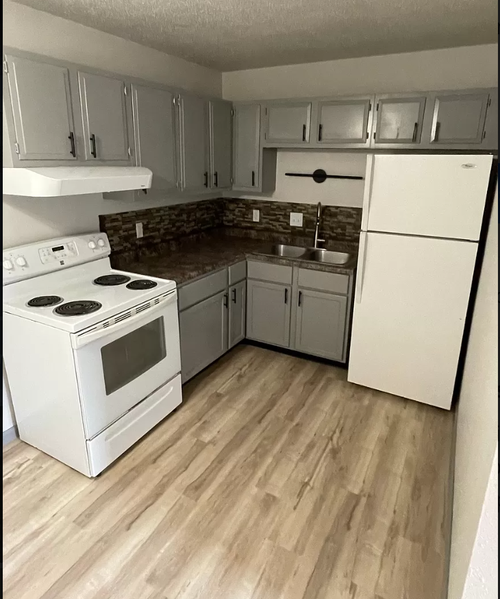 an empty kitchen with white appliances and white cabinets