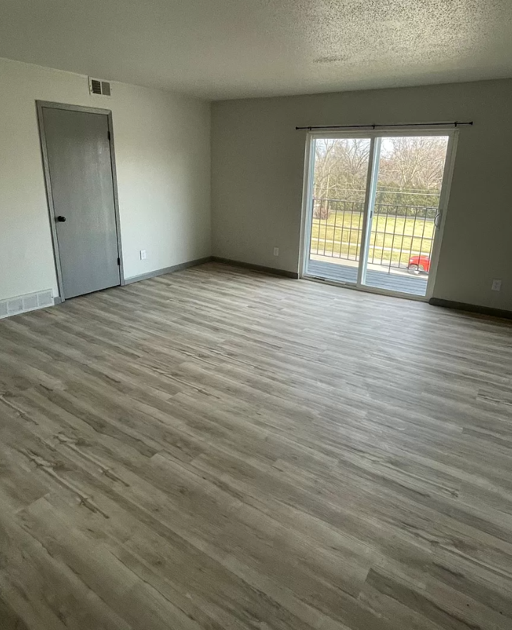an empty living room with wooden floors and a sliding glass door
