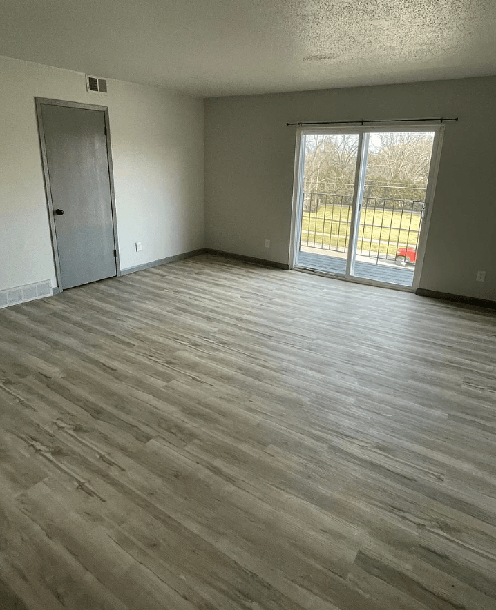 an empty living room with wooden floors and a sliding glass door