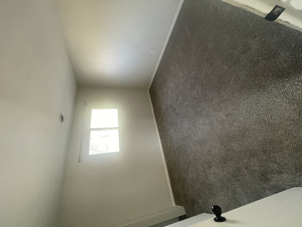 a small window in the corner of a room with a white wall and a ceiling