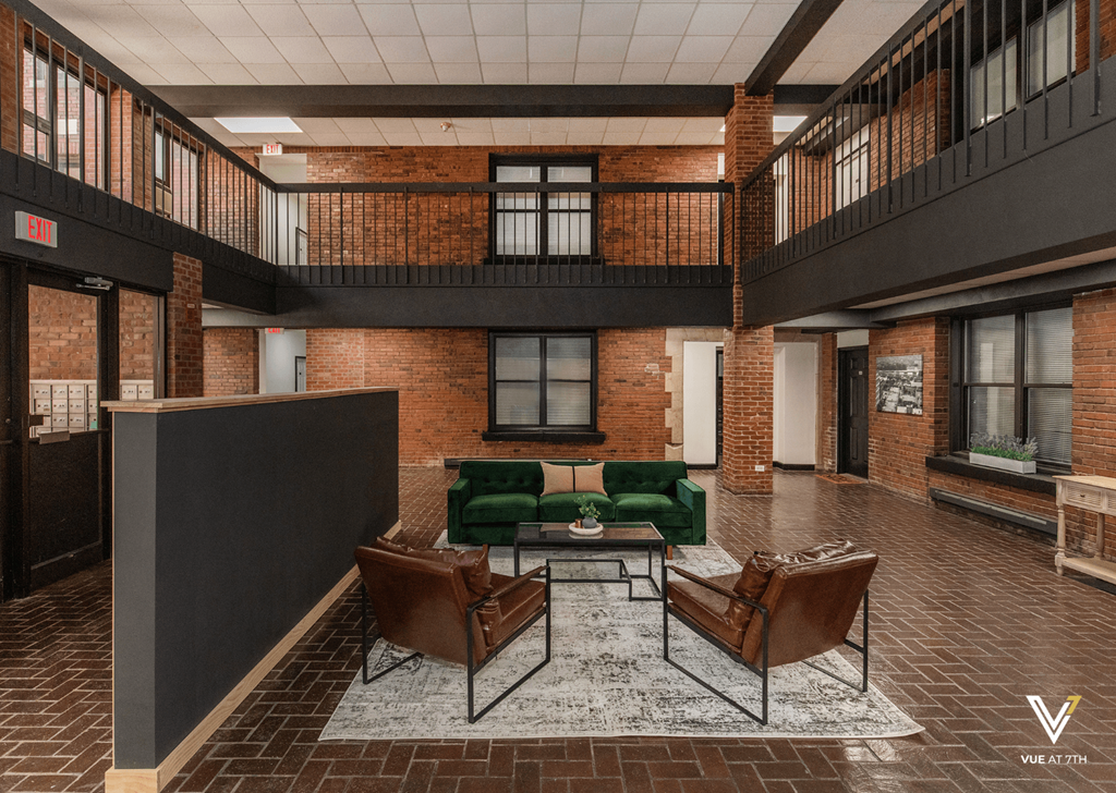 a large lobby with a green couch and leather chairs