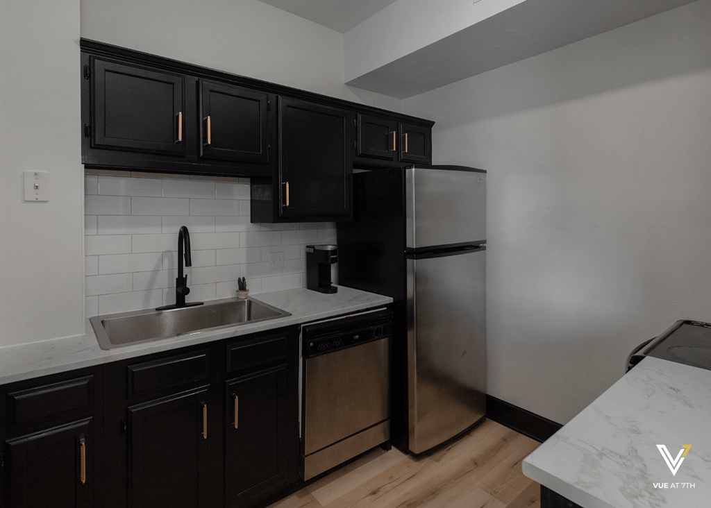 an empty kitchen with black cabinets and a stainless steel refrigerator