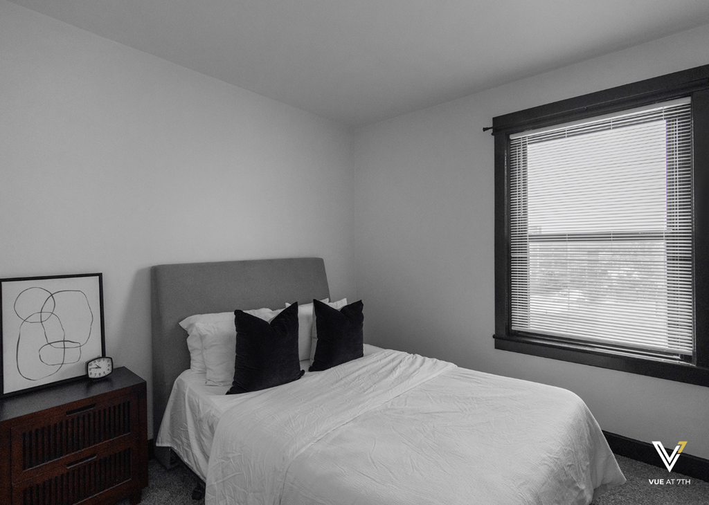 an empty bedroom with a bed and a window