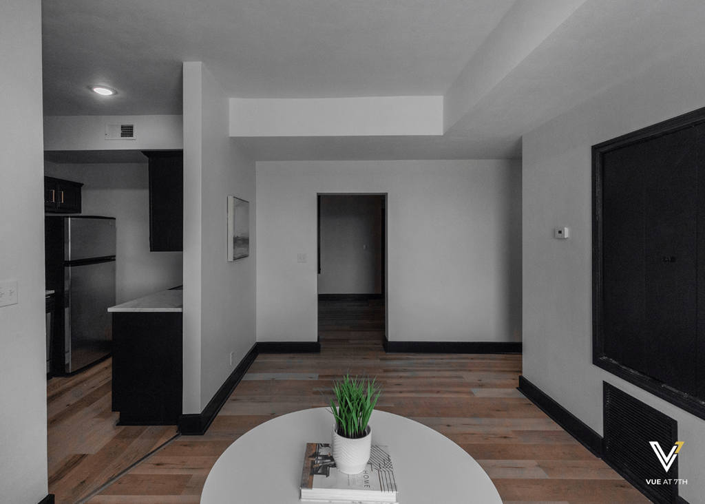 an empty living room with a table and a kitchen