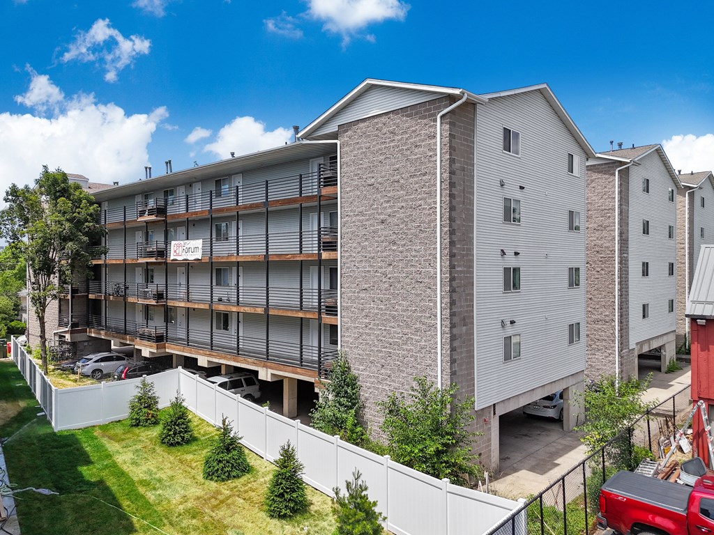 an apartment building with balconies and a red car parked in front