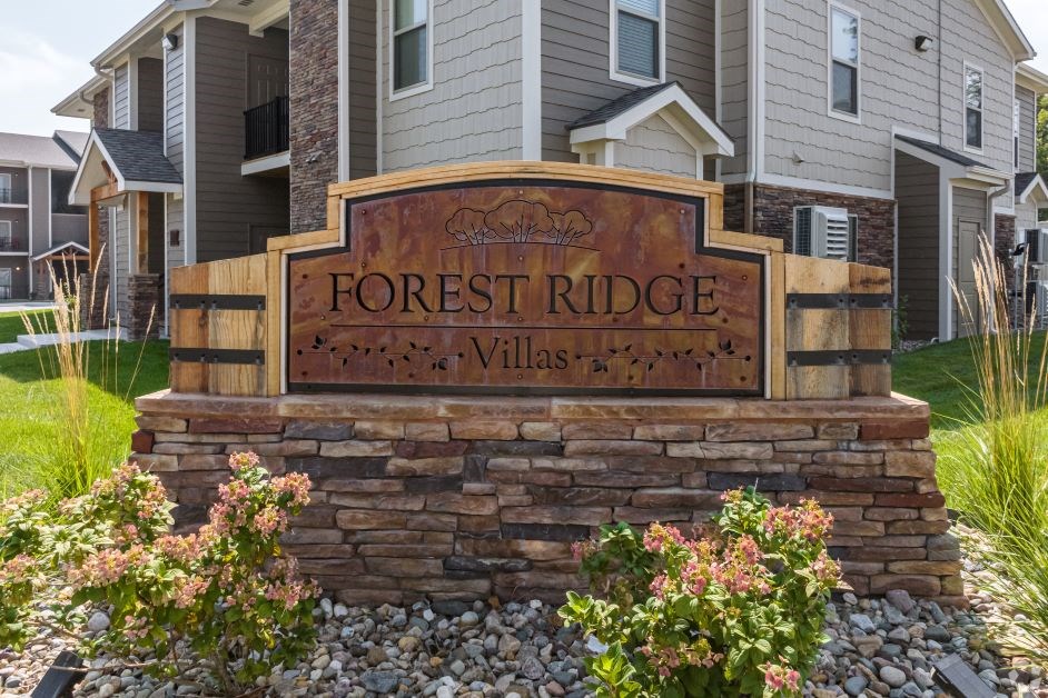 A sign that says Forest Ridge Villas in front of some houses.