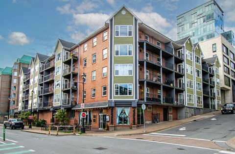 A street view of a multi-story building with a red stop sign in front of it.