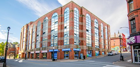 A large red brick building with many windows sits on a street corner.