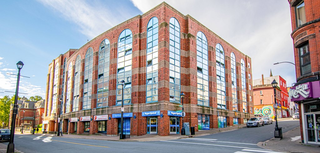 A large red brick building with many windows sits on a street corner.