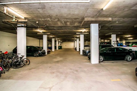 A parking garage with cars and bicycles.