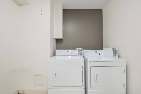 Two white washing machines in a laundry room.