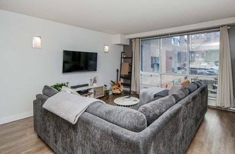 A grey couch with a white pillow and a grey blanket on it.