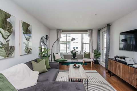 A living room with a grey couch, a coffee table, and a large window.