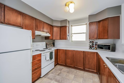 A kitchen with brown cabinets and a white refrigerator.