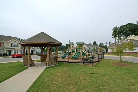 A gazebo is in the middle of a playground with a slide.
