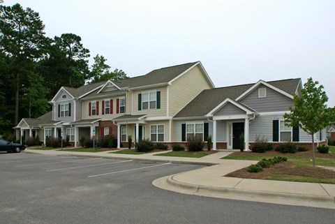 A row of houses with a car parked in front of the first house.
