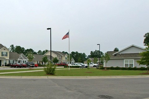 A street view of a residential area with houses and cars.