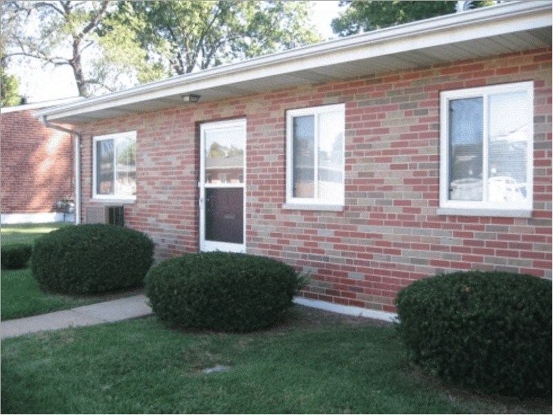 a brick house with grass and bushes in front of it