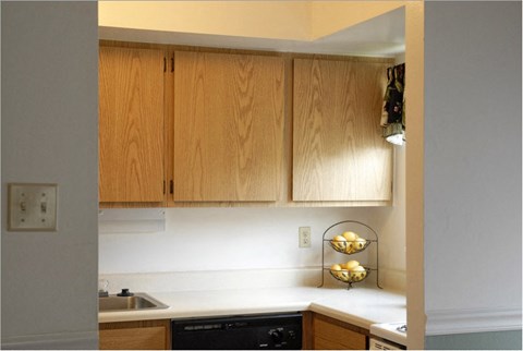 a kitchen with wooden cabinets and a black dishwasher