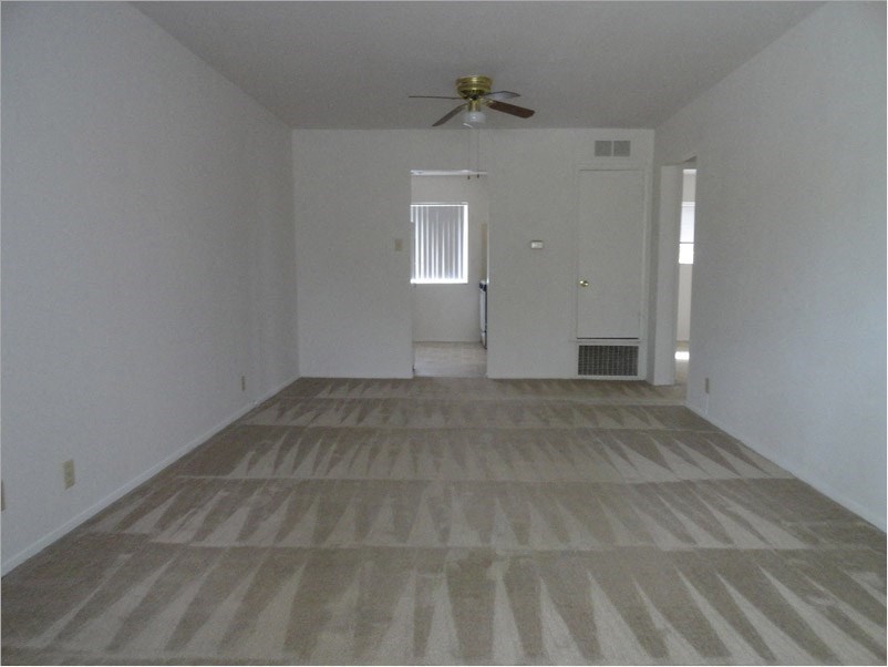 an empty living room with white walls and a ceiling fan