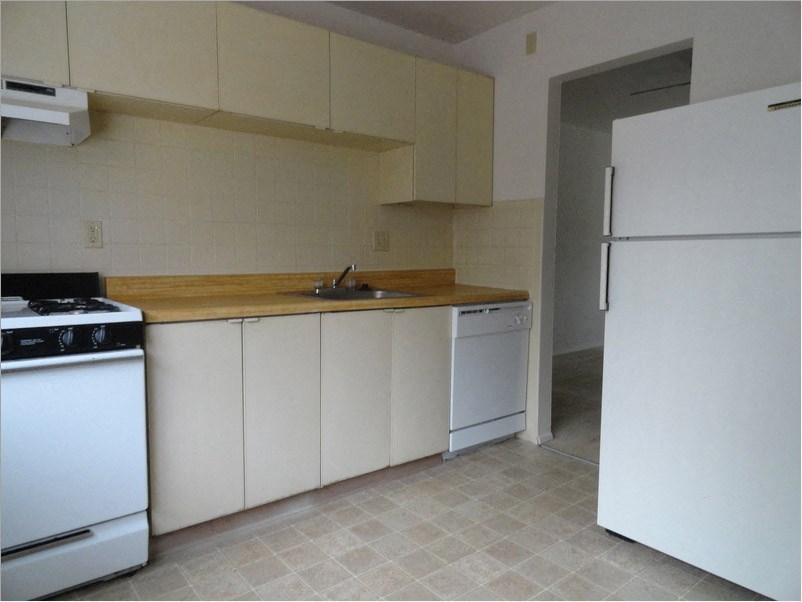 an empty kitchen with white appliances and a sink