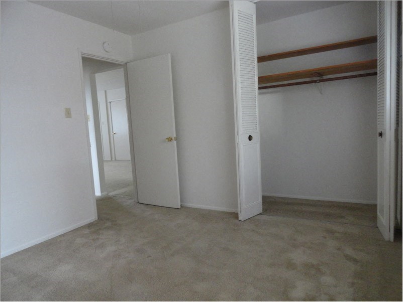 an empty room with white walls and a door to a closet