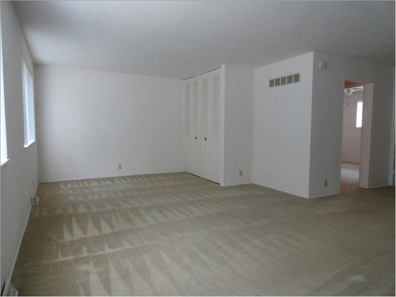 an empty living room with white walls and a wooden floor