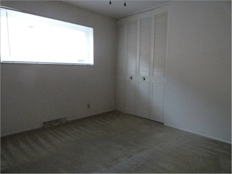 an empty room with a window and a closet