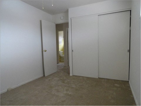 a bedroom with white walls and doors and a carpeted floor