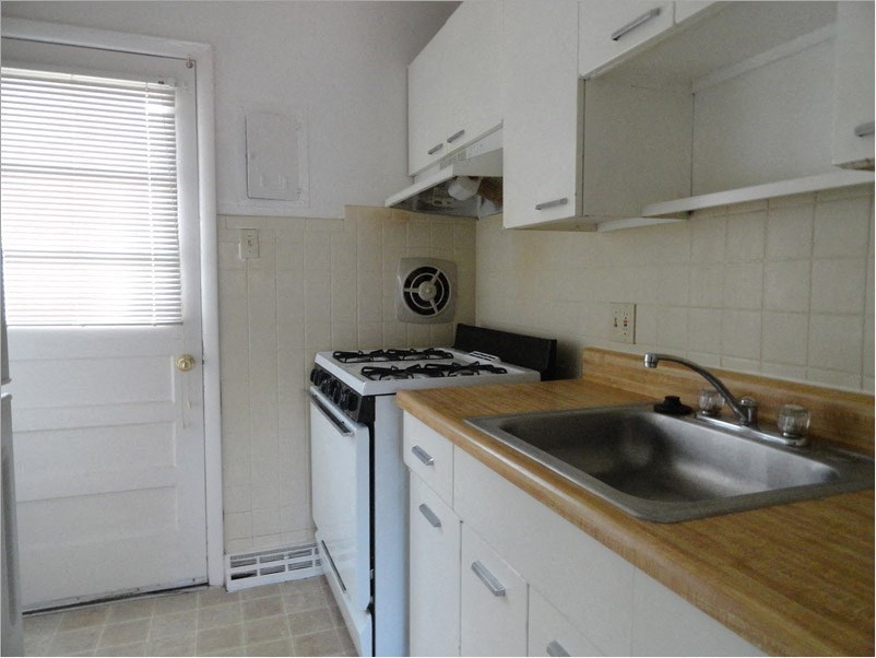 an empty kitchen with white appliances and a sink