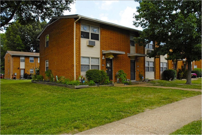 a brick apartment building with a sidewalk in front of it