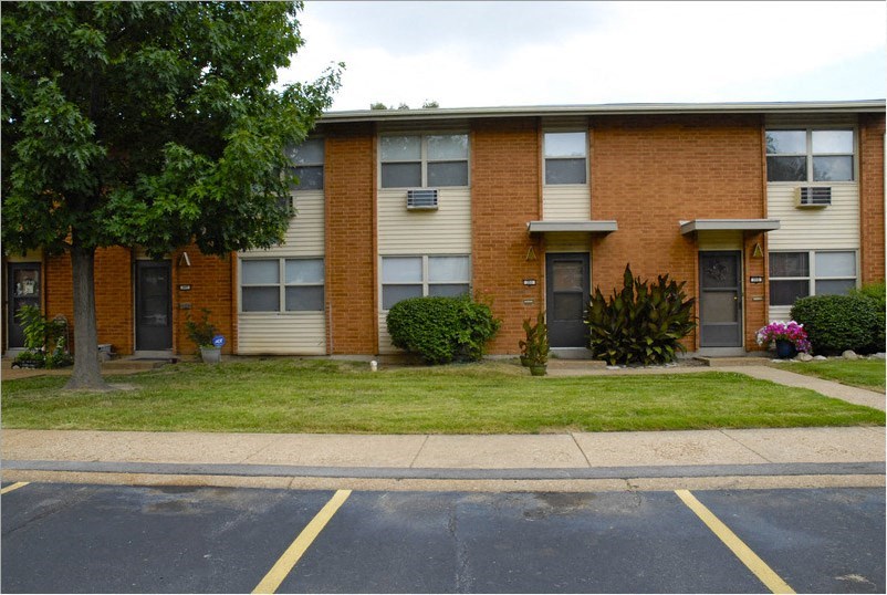 a brick apartment building with a lawn in front of it