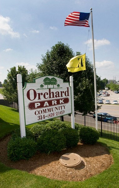 a sign for orchard park community with an flag