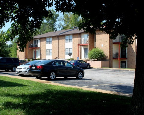 a parking lot with cars in front of a brick apartment building